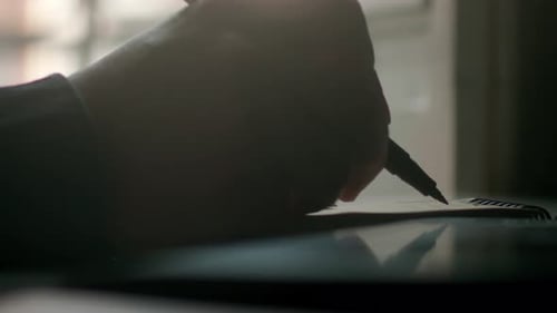Extreme close up of a man writing and designing with his hand and a pen on a paper notebook in super