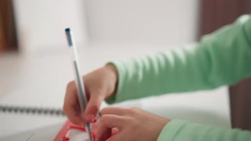 Child Using Ruler and Pen on a Notepad