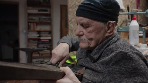 Un maître masculin âgé travaille dans son atelier de restauration de meubles