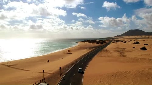 Desertic road crossed by a car at the coast of Fuerteventura
