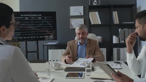 Clinical Manager Holding Discussion with Team of Doctors at Meeting in Office