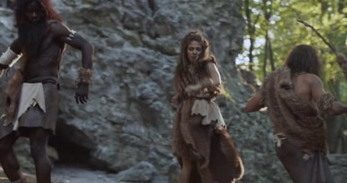 Slow Motion Tribe of Cavemen Neanderthals Wearing Animal Skin Holding Weapon Dancing Having Fun in