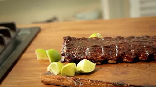Succulent Glazed Barbecue Ribs with Fresh Lime Wedges on Wooden Board