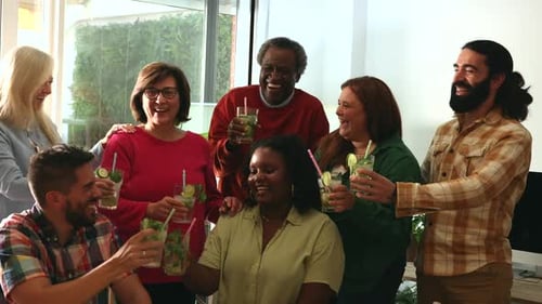 group of multiracial and mixed age friends toasting with mojitos at a house party