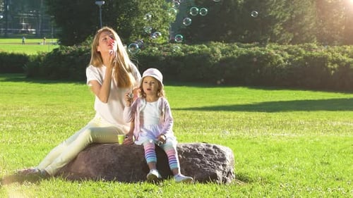 Mother and Daughter Blowing Bubbles at Park