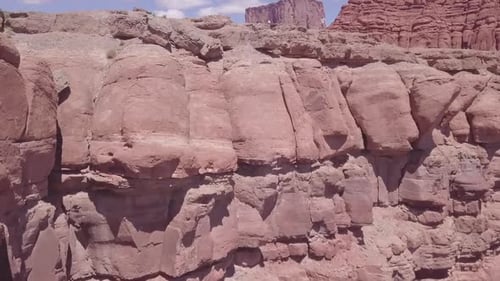 Red rocky cliff with three motorcycle riders standing on top close to the edge, aerial
