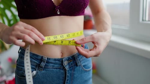Slim Young Girl Holding Tape Measure on Her Thin Waist