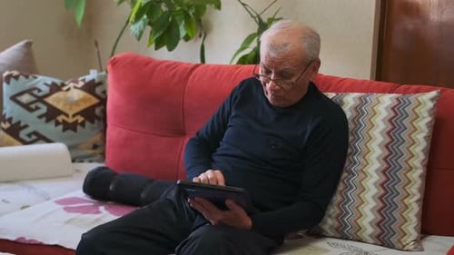 Senior Man Relaxing on Couch Using Tablet