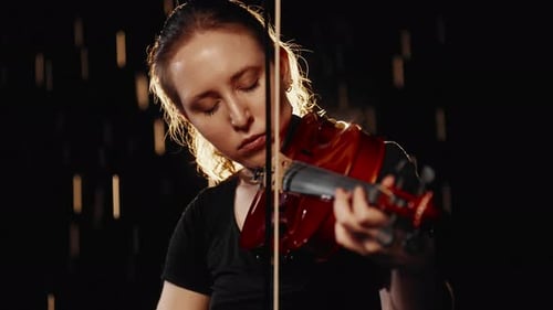 Woman Playing Violin in Dark Studio