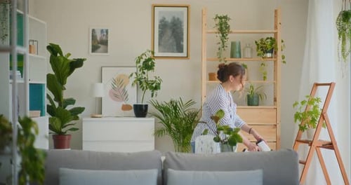 Woman Watering Indoor Plants in Bright Living Room