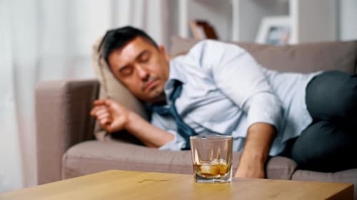 Man on couch takes a drink and rests
