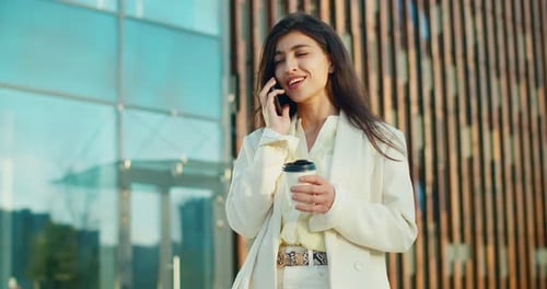 Professional Woman on Phone Holding Coffee Outdoors