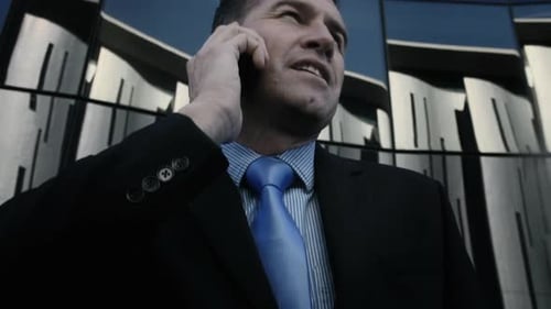Suits Business Man Talking on His Mobile Phone in Modern Glass City