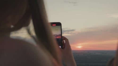 Close Back View of Woman Taking Photo of Horizon at Sunset
