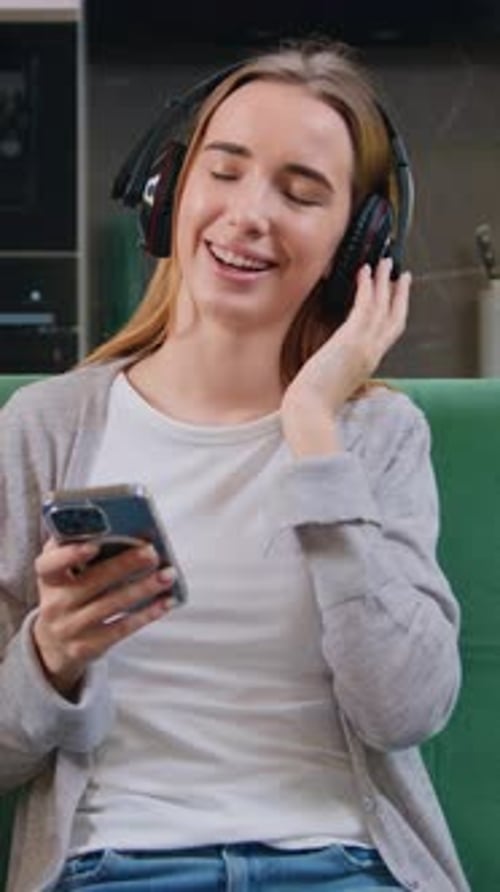 Smiling Woman Listens to Music with Headphones Indoors