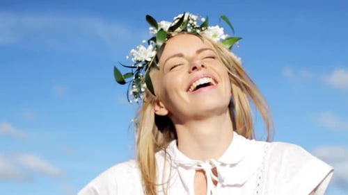 Smiling blonde woman with flower crown against blue sky