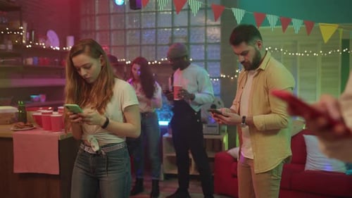 Partygoers Using Smartphones at Colorful Indoor Party