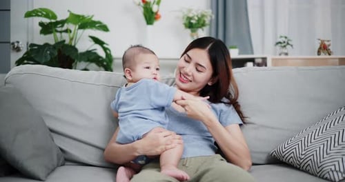Caring Mother Holding Baby on Couch at Home