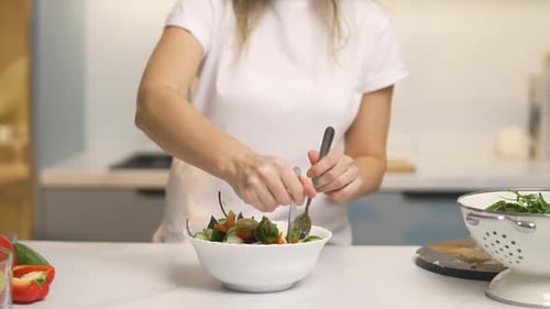Woman preparing healthy salad in bright kitchen