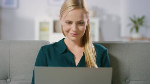 Woman Smiles While Working on Laptop at Home