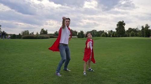 Superhero Father and Son Posing in a Grassy Field