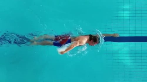 Nadador profesional de estilo libre entrenando en piscina, rastreando tomas aéreas