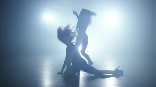 Two Dancers Performing Expressive Choreography on a Foggy Stage