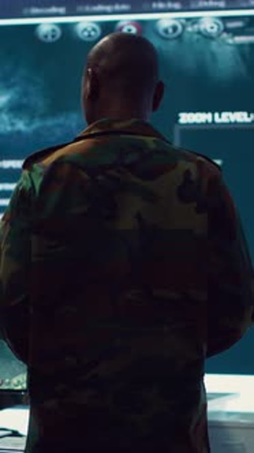 Man in Camouflage Looking at Screen in Dark Room