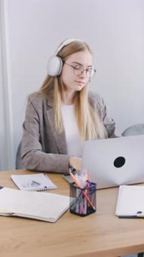 Woman Works on Laptop with Headphones at Desk