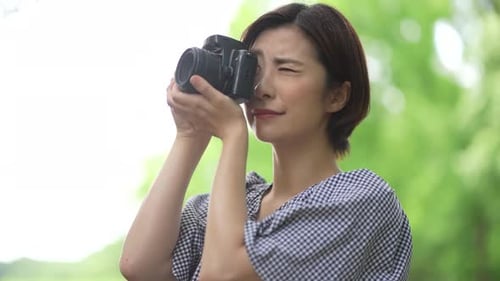 Woman Taking Pictures with Camera in Park