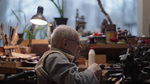 Senior Elderly Master Jeweler in Wheelchair Works in a Workshop