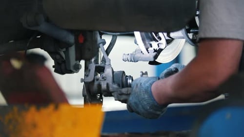 Mechanic Working on Car Brakes in Garage