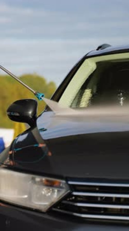 Man Washing Car with HighPressure Water at Outdoor Car Wash
