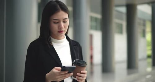 Young Woman Checking Phone with Coffee in Urban Setting