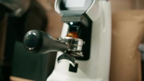 Professioneller Barista-Arbeiter mahlen mit der Schleifmaschine frische Kaffeebohnen für die Zubereitung von Heißgetränken