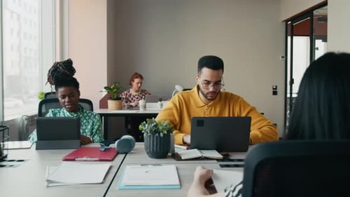 Travailleurs indépendants travaillant sur des appareils numériques dans un bureau de coworking