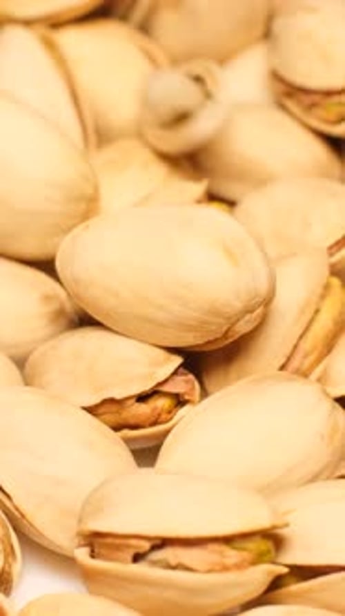 A Pile of Salted Roasted Pistachios Falls Into a Plate in Slow Motion Vertical Video