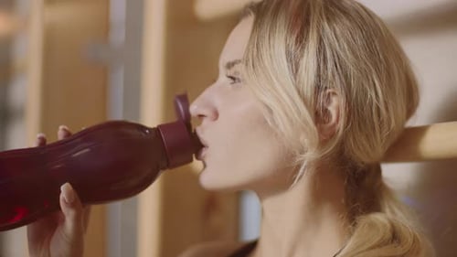 Relaxed Sport Woman Drinking Water in Fitness Gym. Portrait of Concentrated Woman