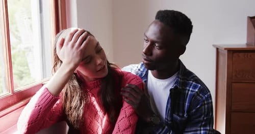 Sad diverse couple embracing and comforting each other at home, slow motion