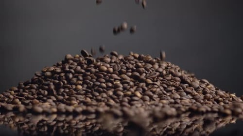 Coffee Beans Pouring on Top Heap Close Up. Roasted Caffeine Grains Falling