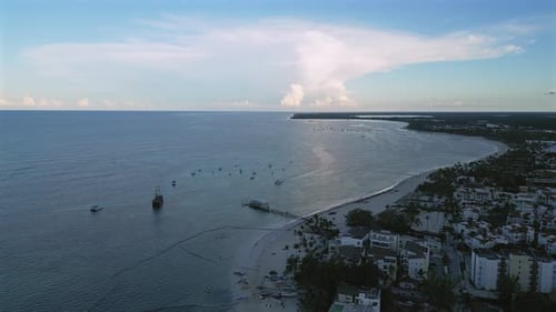Drone shot of a white sand coastline with crystal clear sea and resorts