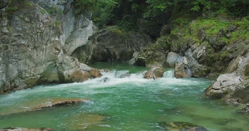 Mountain river with turquoise water in a narrow gorge at rainy day. Rapid clear fresh water flows am