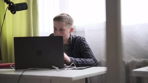 Concentrated Boy Working on Laptop at Desk