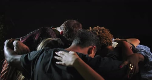 Group of people including African American and Latin Hispanic individuals embracing in tight circle