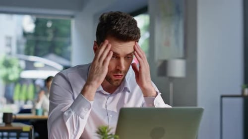 Man Working on Laptop in Bright Office, Thinking