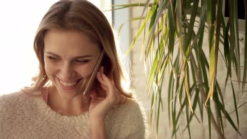 Smiling woman enjoys phone call at home, daytime