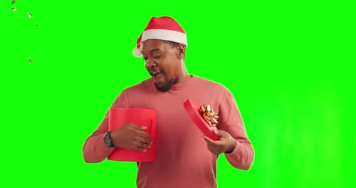 Black man, Christmas gift and confetti on green screen in surprise for festive holiday