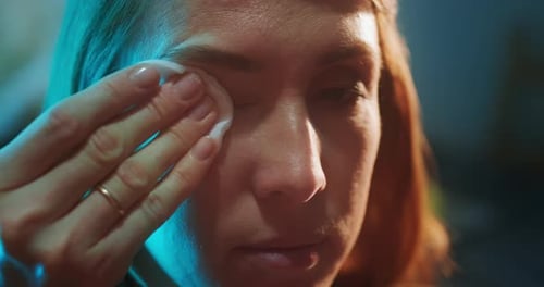 Woman cleans her eye. Young woman cleans her eye from make up, extreme close up shot of the mascara