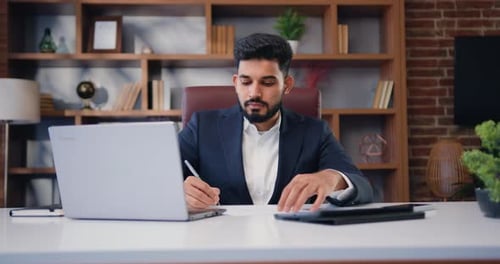 Businessman Leader Using Laptop with Working Papers at Office Desk at Modern Office Room