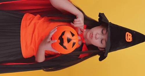 Girl in Witch Costume Holds Halloween Pumpkin